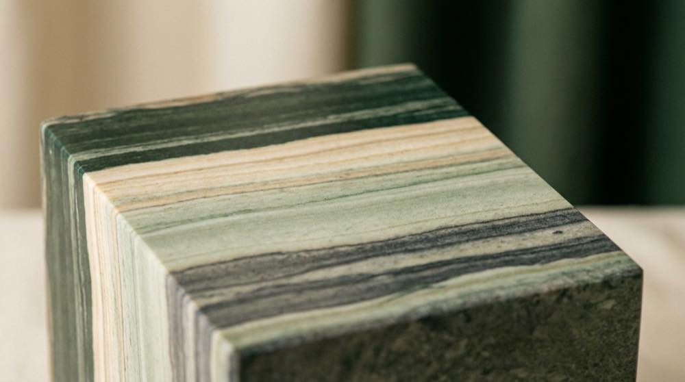 Polished cross-section of layered green and cream stone